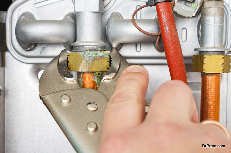 Plumber repairing a leaking gas boiler of a heating home system.